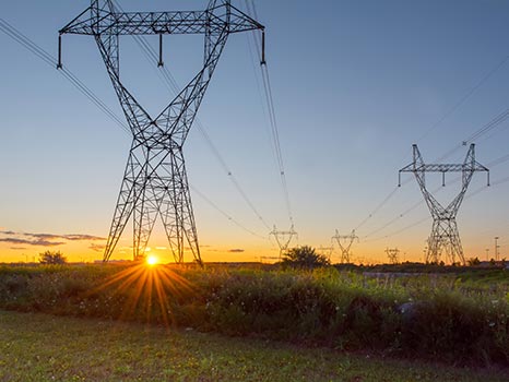 des poteaux électriques dans un champ au coucher du soleil